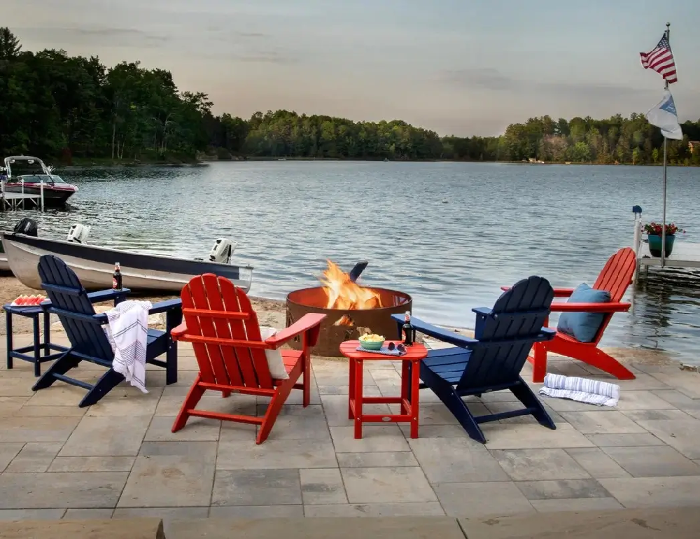 Lakeside patio featuring red and blue Adirondack chairs gathered around a fire pit for evening relaxation and socializing.